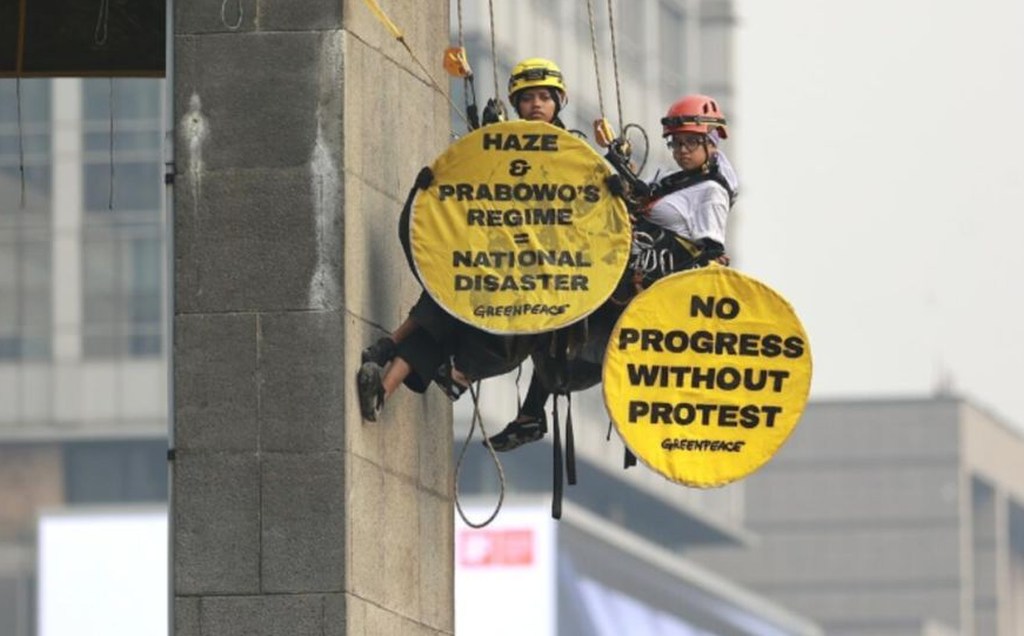 Aktivis Greenpeace membentangkan spanduk tuntutan penanganan krisis iklim dan penurunan biaya hidup di Bundaran HI, Jakarta.
